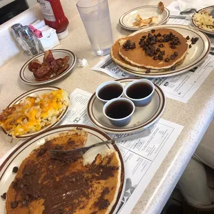 a breakfast of pancakes, eggs, bacon, and coffee