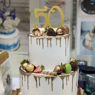 a three tiered cake with chocolate covered strawberries and strawberries