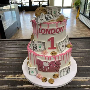 a three tiered cake decorated with money and cookies