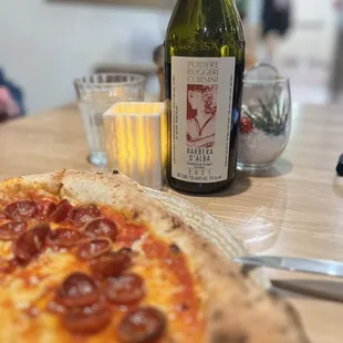 a pepperoni pizza and a bottle of wine