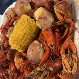a tray of crawfish, corn and potatoes
