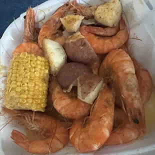 shrimp, potatoes, corn and potatoes in a styrofoam container