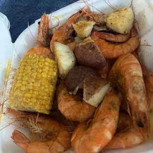 shrimp, potatoes, corn, and potatoes in a styrofoam container
