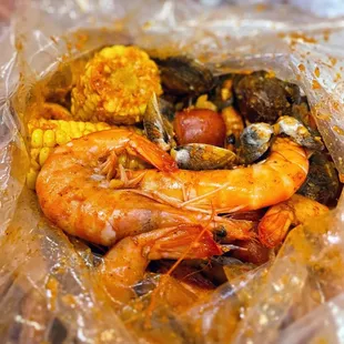 shrimp, corn, corn, and potatoes in a plastic bag