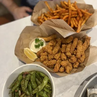 a plate of fried fish, a bowl of fries, and a bowl of green beans