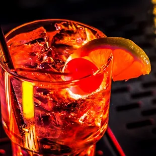 a drink with a cherry and lime garnish