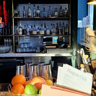 a bar with bottles of alcohol and a basket of fruit