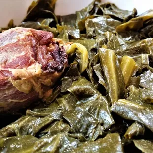 a bowl of collard greens with a piece of meat