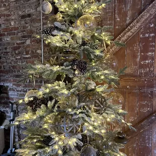 a decorated christmas tree in front of a brick wall