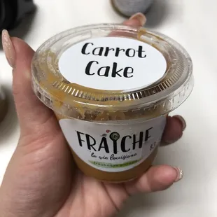 a hand holding a cup of carrot cake