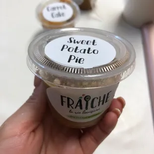 a hand holding a cup of sweet potato pie