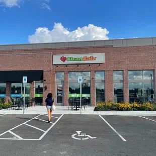 a woman walking in front of a clean eatz restaurant