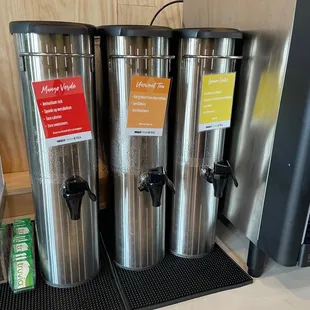 three stainless steel coffee dispensers on a counter