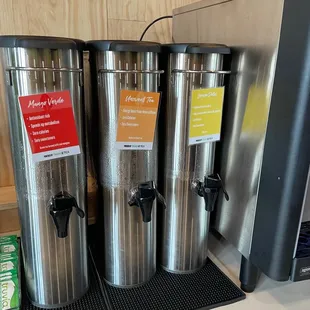 three stainless steel coffee urns on a counter