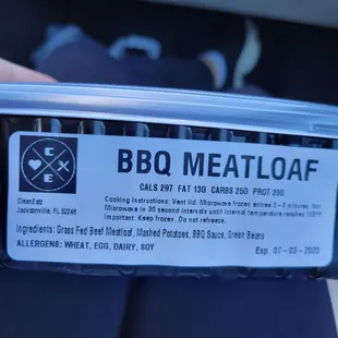 a person holding a container of meatloaf