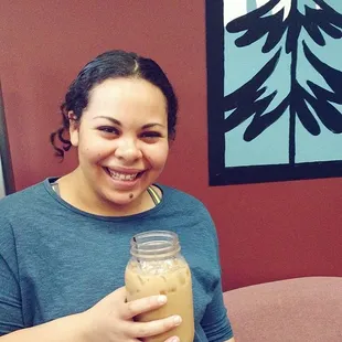 a smiling woman holding a jar of coffee
