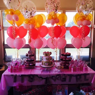 a table with balloons and a cake