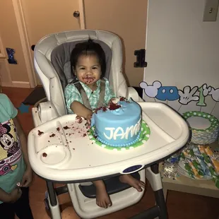 a baby in a highchair with a birthday cake