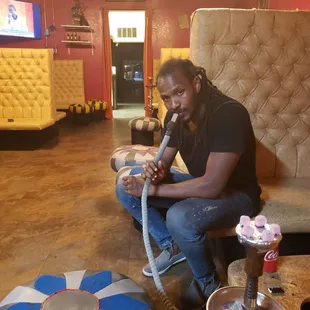 a man sitting on a couch smoking a hook