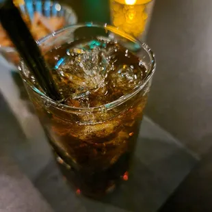 a glass of cola with ice and a straw