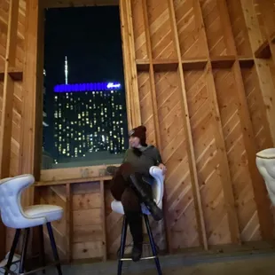 a man sitting at a table with a view of a city at night