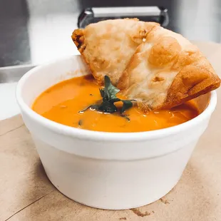 a bowl of soup with a piece of bread sticking out of it
