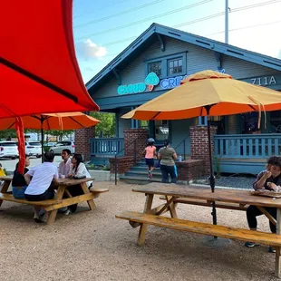 people sitting at picnic tables under umbrellas