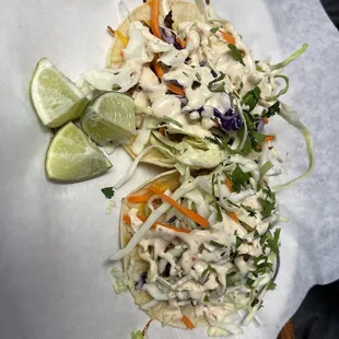 a taco with coleslaw and a lime wedge