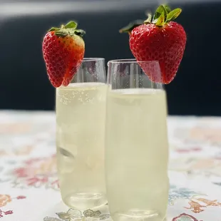 two glasses of champagne with strawberries on top