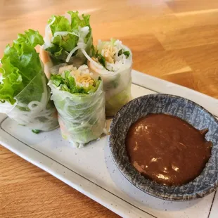 a plate of fresh spring rolls with dipping sauce