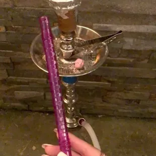 a hand holding a purple candle and a purple stick