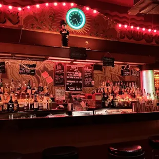 a bar with stools and a neon sign