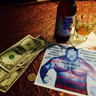 a bottle of beer, money, and a poster on a table