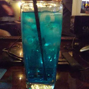 a tall glass of blue liquid with a straw