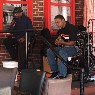 a man sitting on a stool playing a guitar