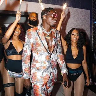 a man in a floral suit with a sparkler in his hand