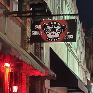 a sign for a bar on a city street