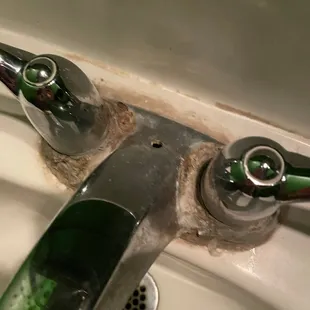 a dirty faucet in a bathroom sink