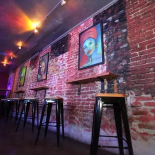 a row of bar stools in front of a brick wall