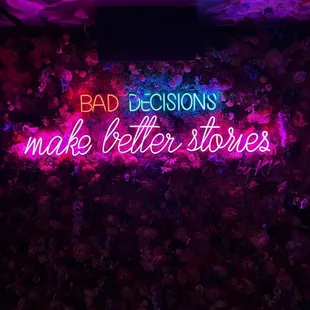 a neon sign that says bad decisions make better stories