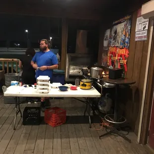 a man in a blue shirt standing in front of a table with food on it