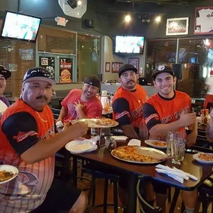 a group of baseball players eating pizza