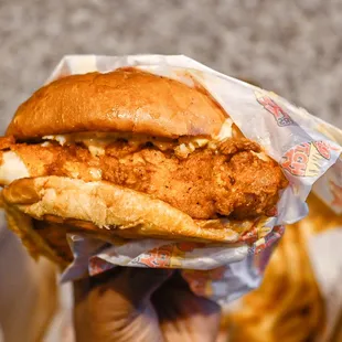 a hand holding a chicken sandwich