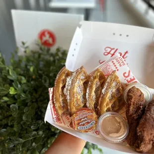 a hand holding a box of donuts