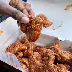 a hand holding a piece of fried chicken