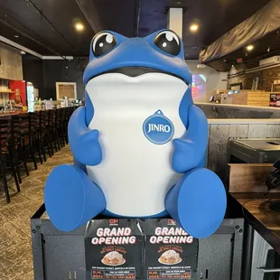 a large blue and white frog sitting on top of two boxes of food