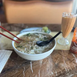 a bowl of noodles and a drink