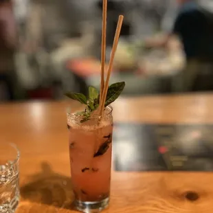 a cocktail with a straw and mint