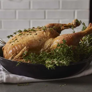 a roast chicken in a pan with herbs