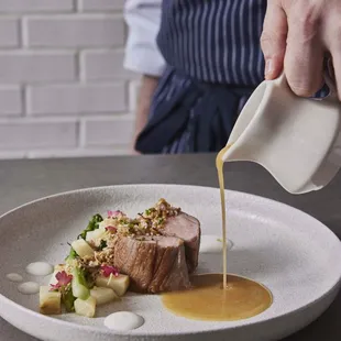 a chef drizzling sauce on a dish